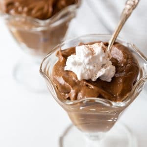 Two glass dishes with chocolate pudding and whipped topping.