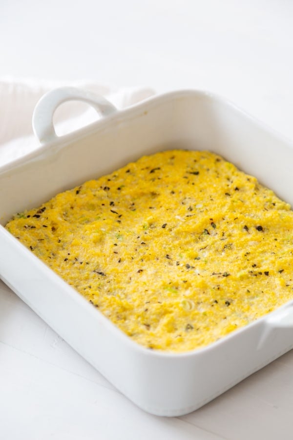 A square white baking dish with herbed polenta . 