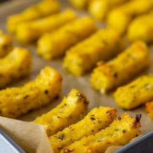 A baking sheet with herbed polenta fries on parchment paper.