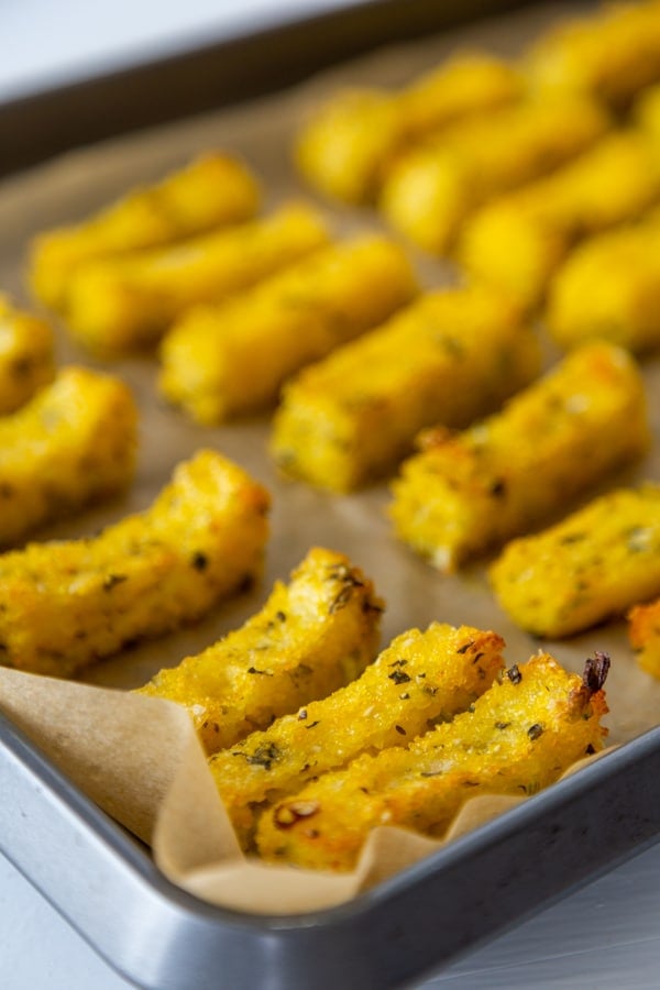 A baking sheet with herbed polenta fries on parchment paper. 