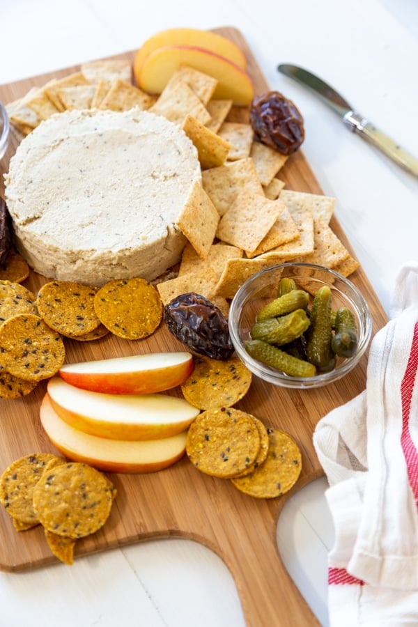 A cheese board with cheese, apples, crackers, and nuts.