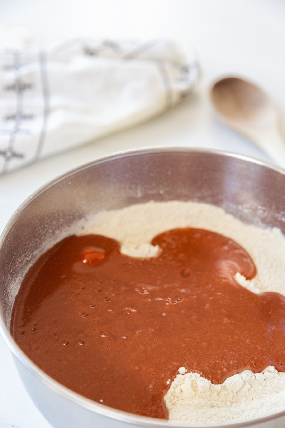 A siver mixing bowl with vital wheat gluten and a red liquid mixture. 