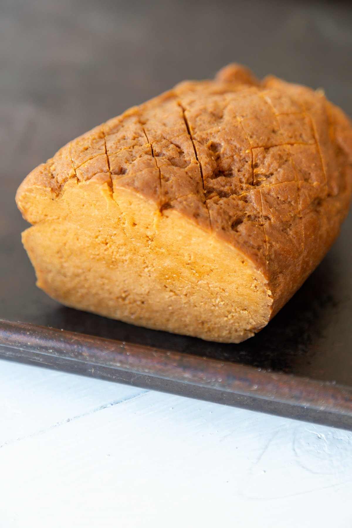 A seitan ham roast with a slice cut from the end of it. 