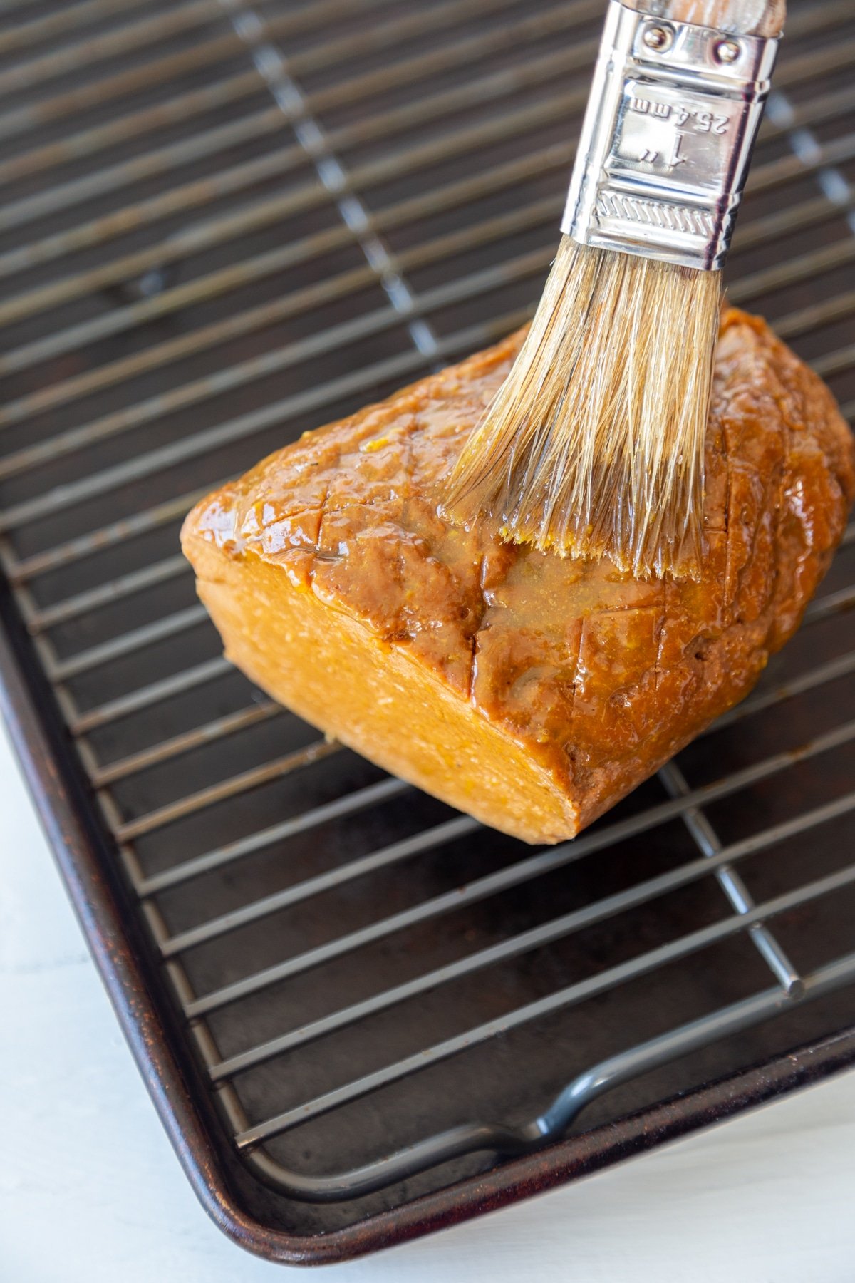 A pastry brush glazing a vegan ham. 