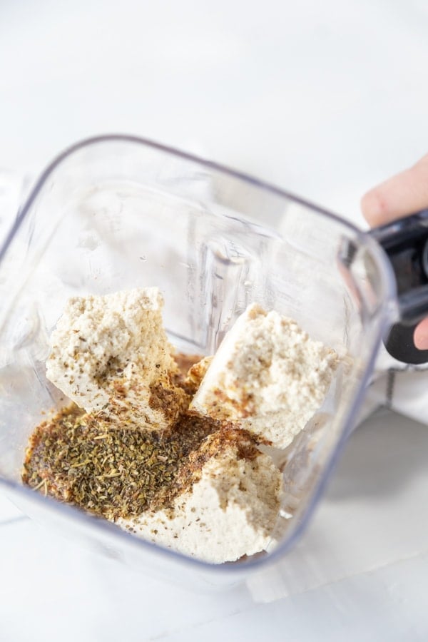 A blender with tofu, nutritional yeast, and seasoning.