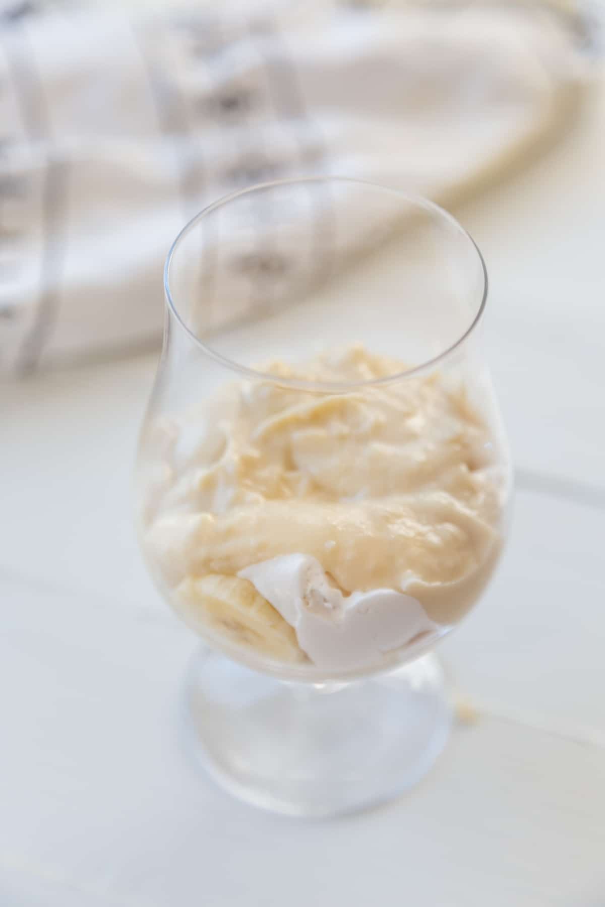 A glass with vanilla pudding and whipped cream.