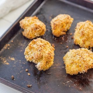 Oven fried breaded cauliflower on a baking sheet with a white and black towel in the background.