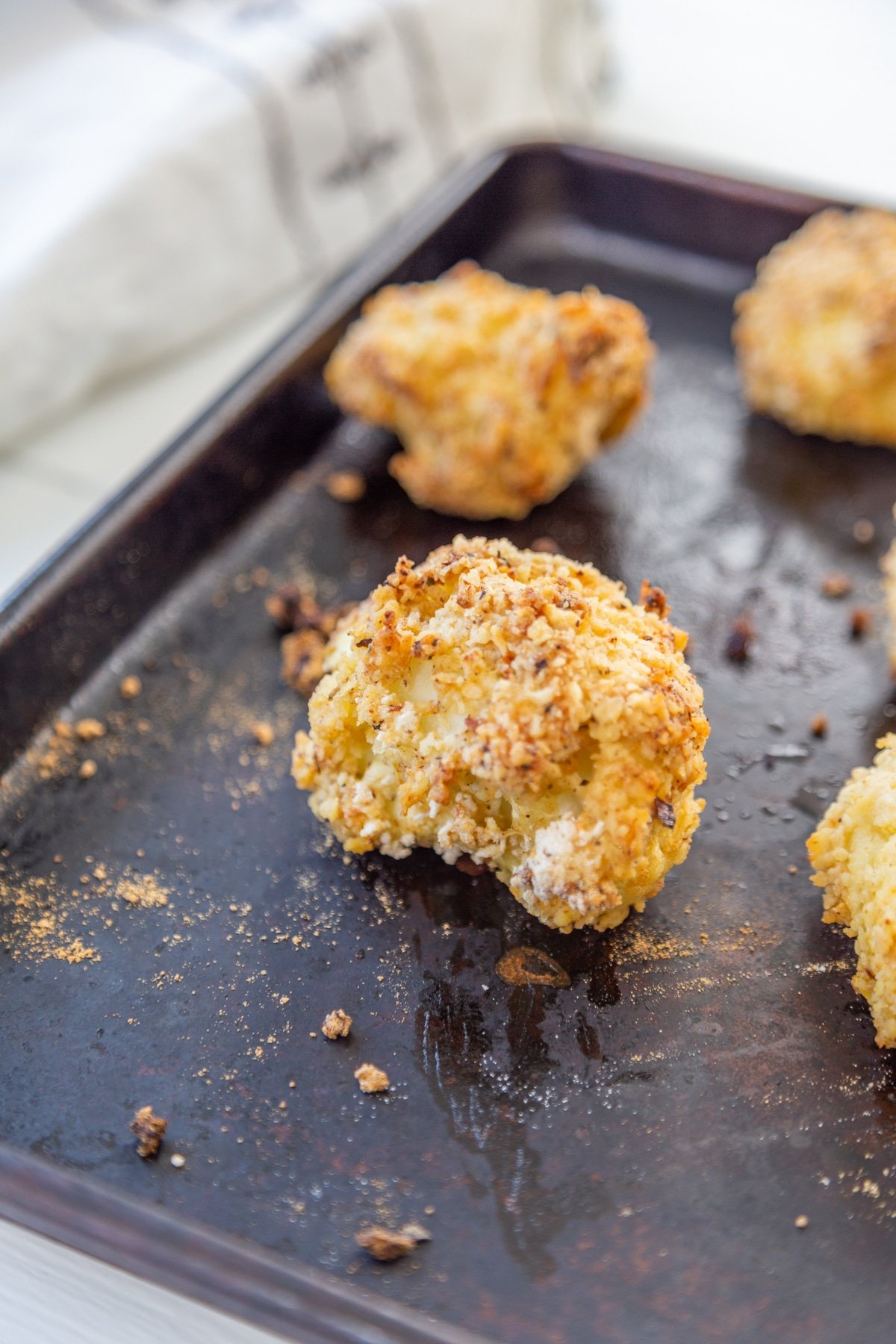 Breaded oven fried cauliflower florets on a baking sheet.