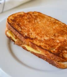 A monte cristo ham and cheese grilled sandwich on a white plate.