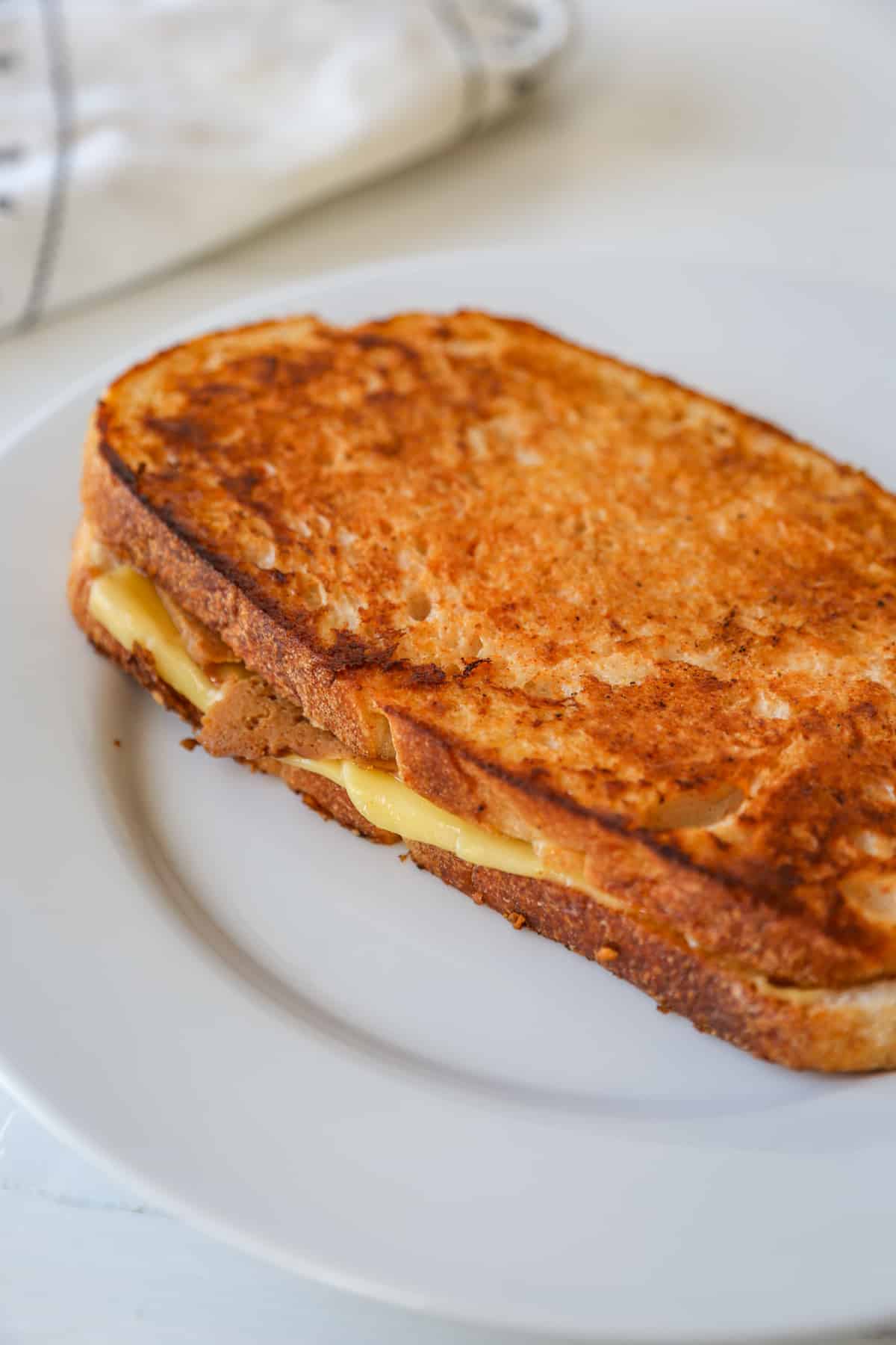 A monte cristo ham and cheese grilled sandwich on a white plate.