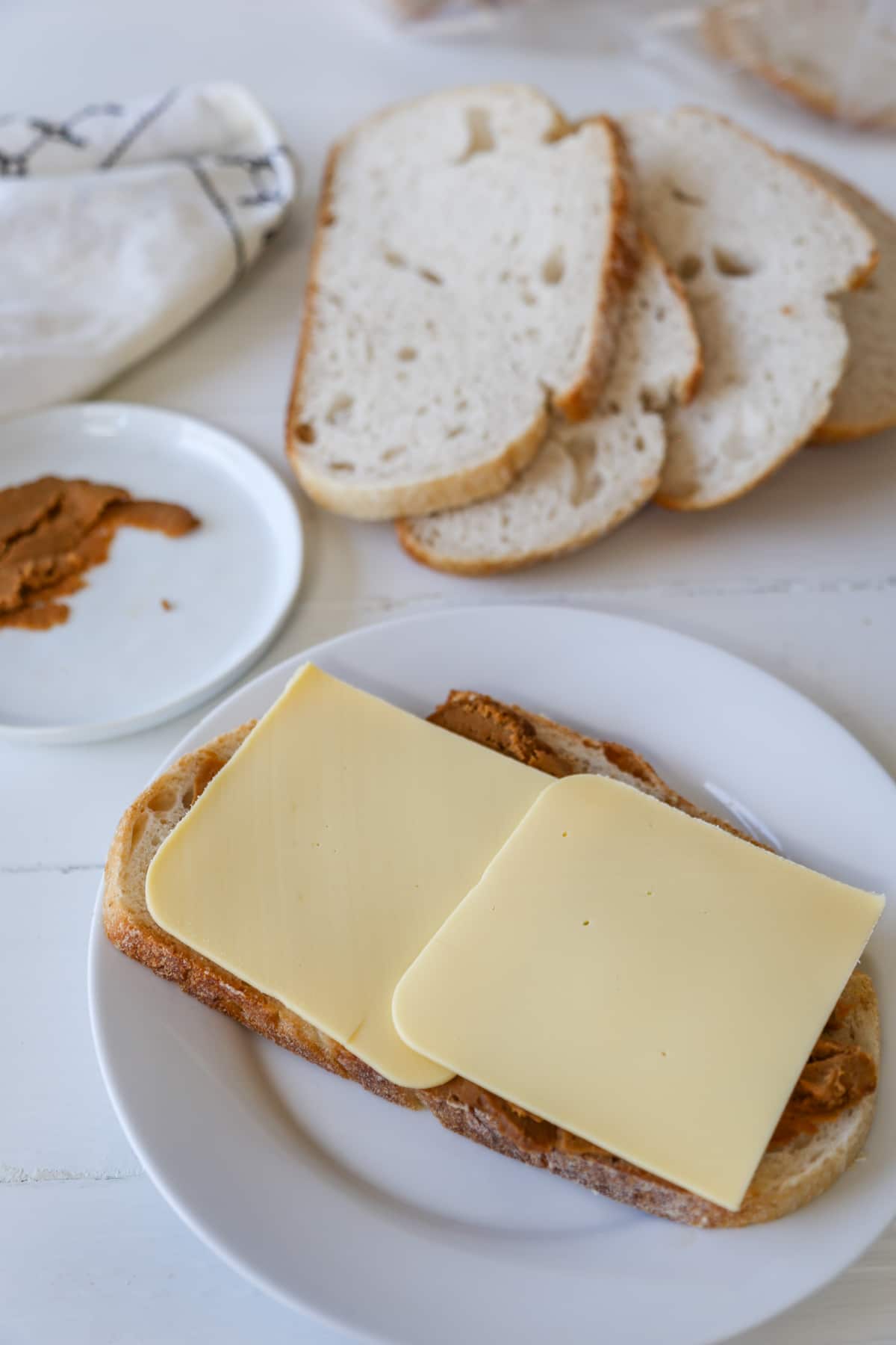 A slice of bread with ham and cheese on it and sliced bread and ham in the background.