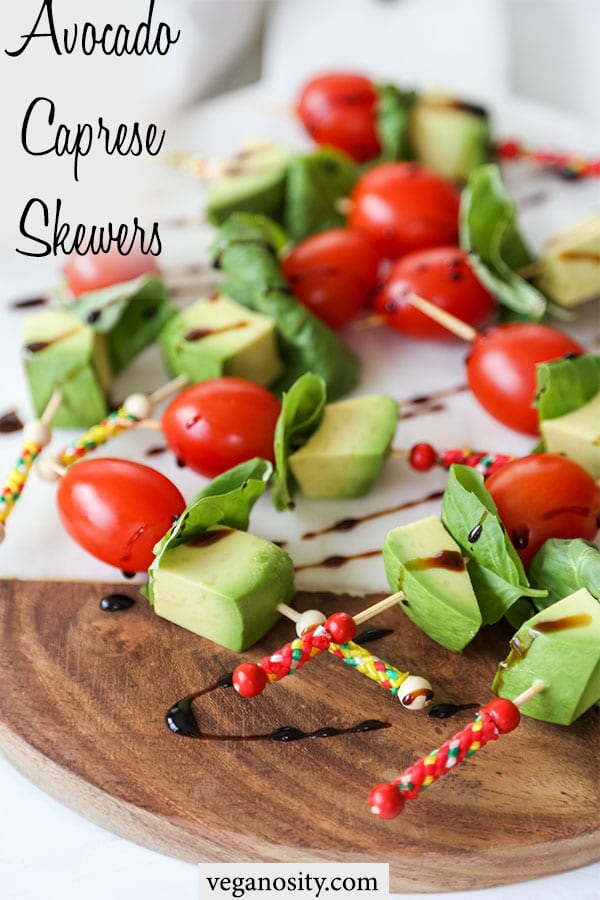 A Pinteres pin for vegan avocado caprese skewers with a picture of the tomato, basil, and avocado skewers drizzled with balsamic vinegar.