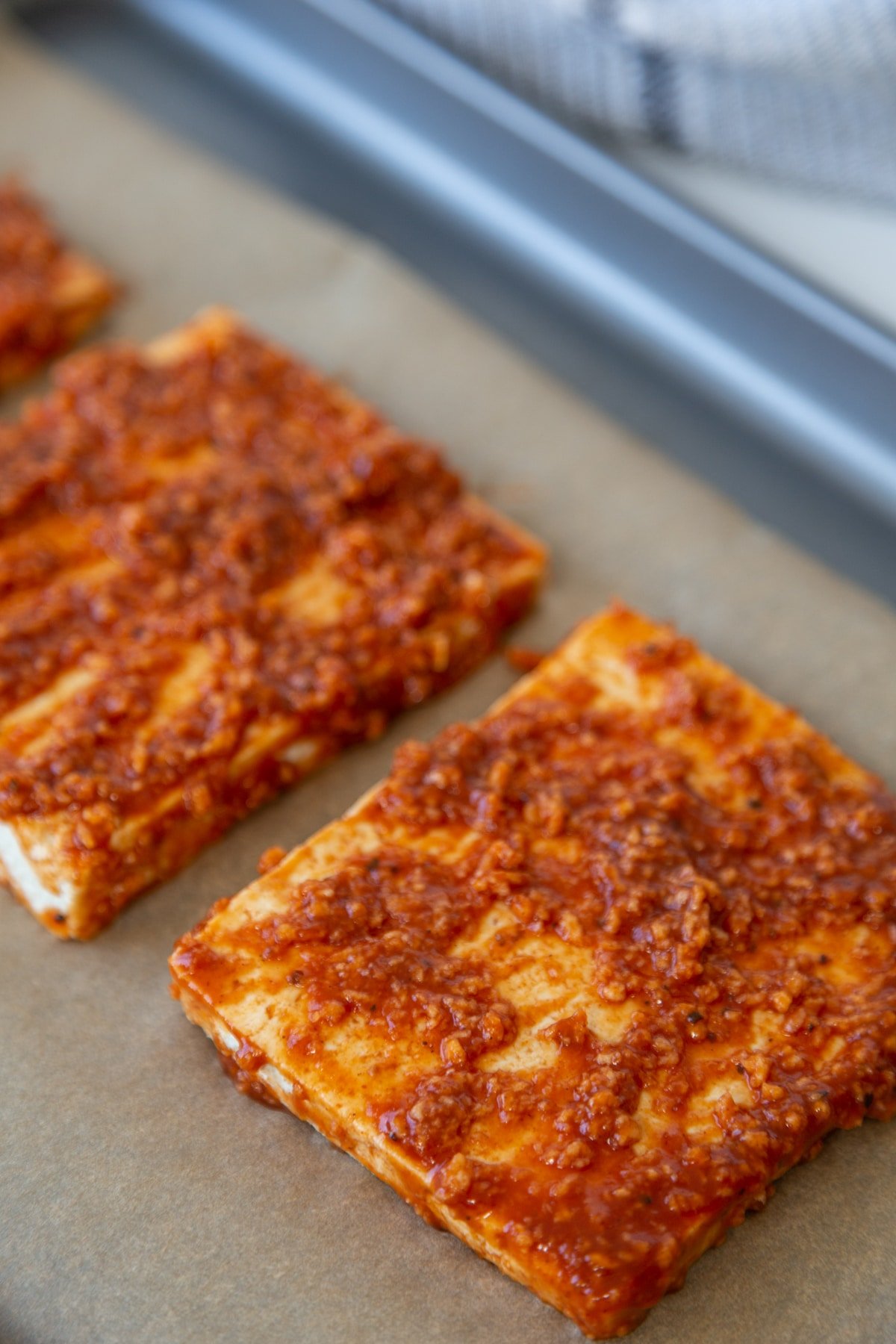 3 barbecue tofu steaks on a baking sheet lined with parchment paper.