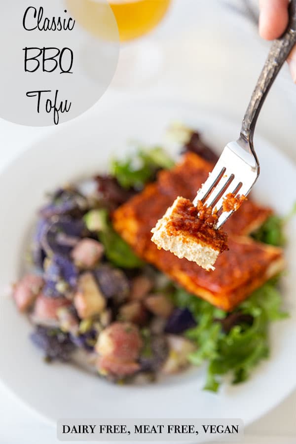 A Pinterest pin for bbq tofu with a picture of a silver fork with a slice of the tofu held above the plate with the tofu and potato salad. 