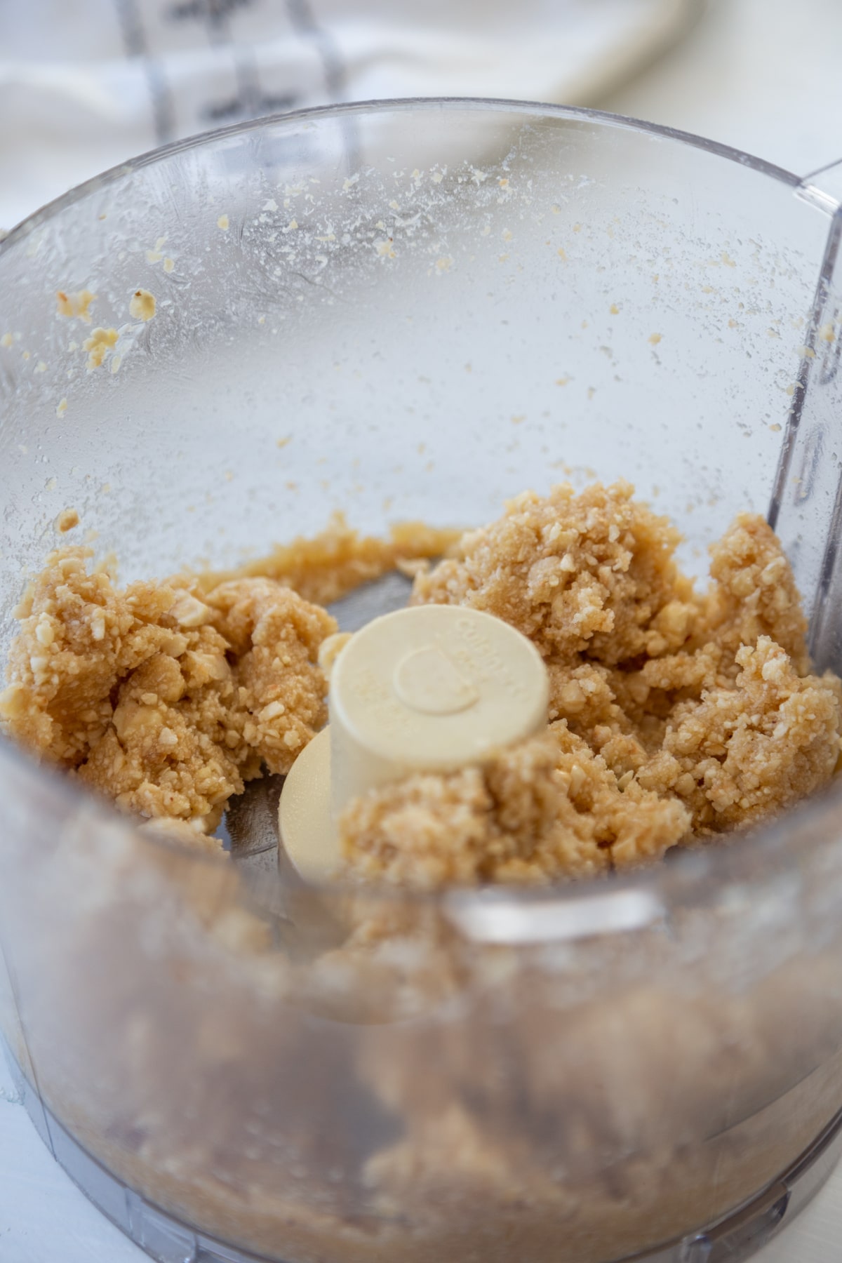 A food processor with processed nuts and coconut.