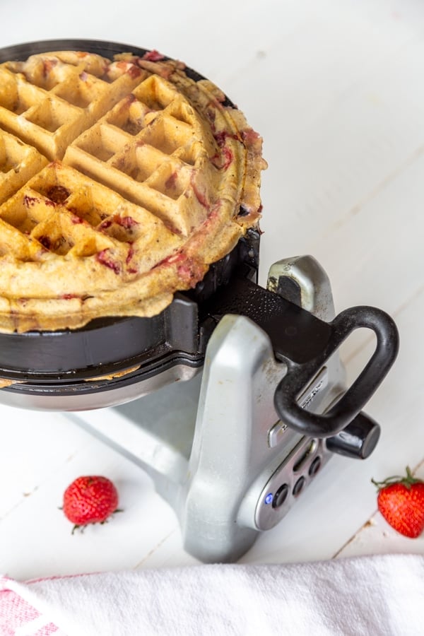 A strawberry pecan waffle in a waffle iron.