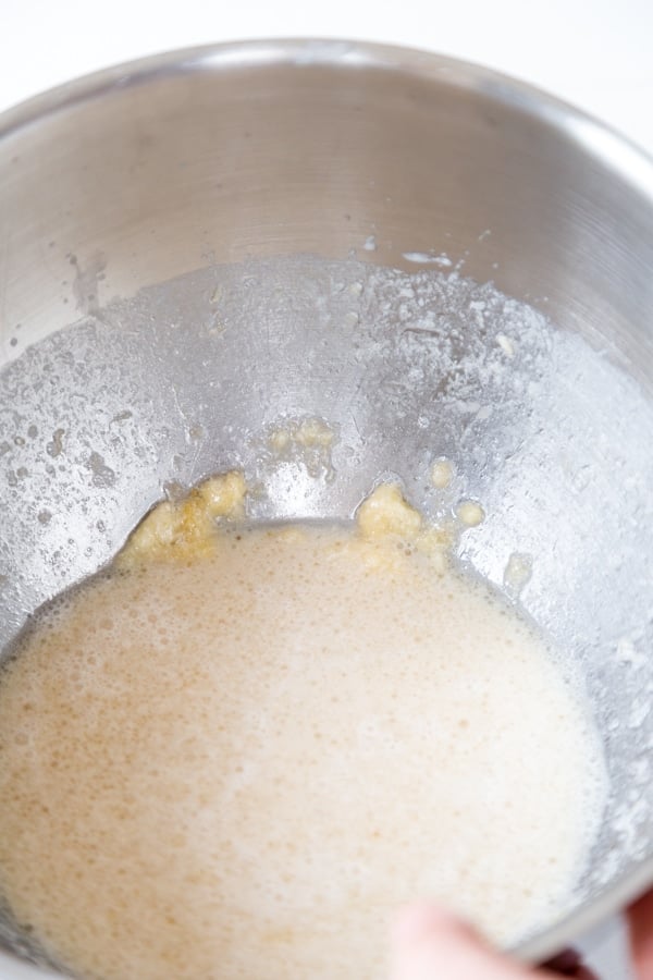A silver mixing bowl with banana puree and milk.