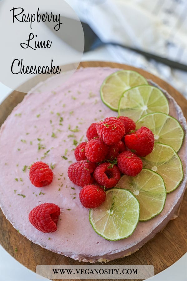 A Pinterest pin for raspberry lime cheesecake with a picture of the whole cake decorated with lime slices and whole raspberries. 