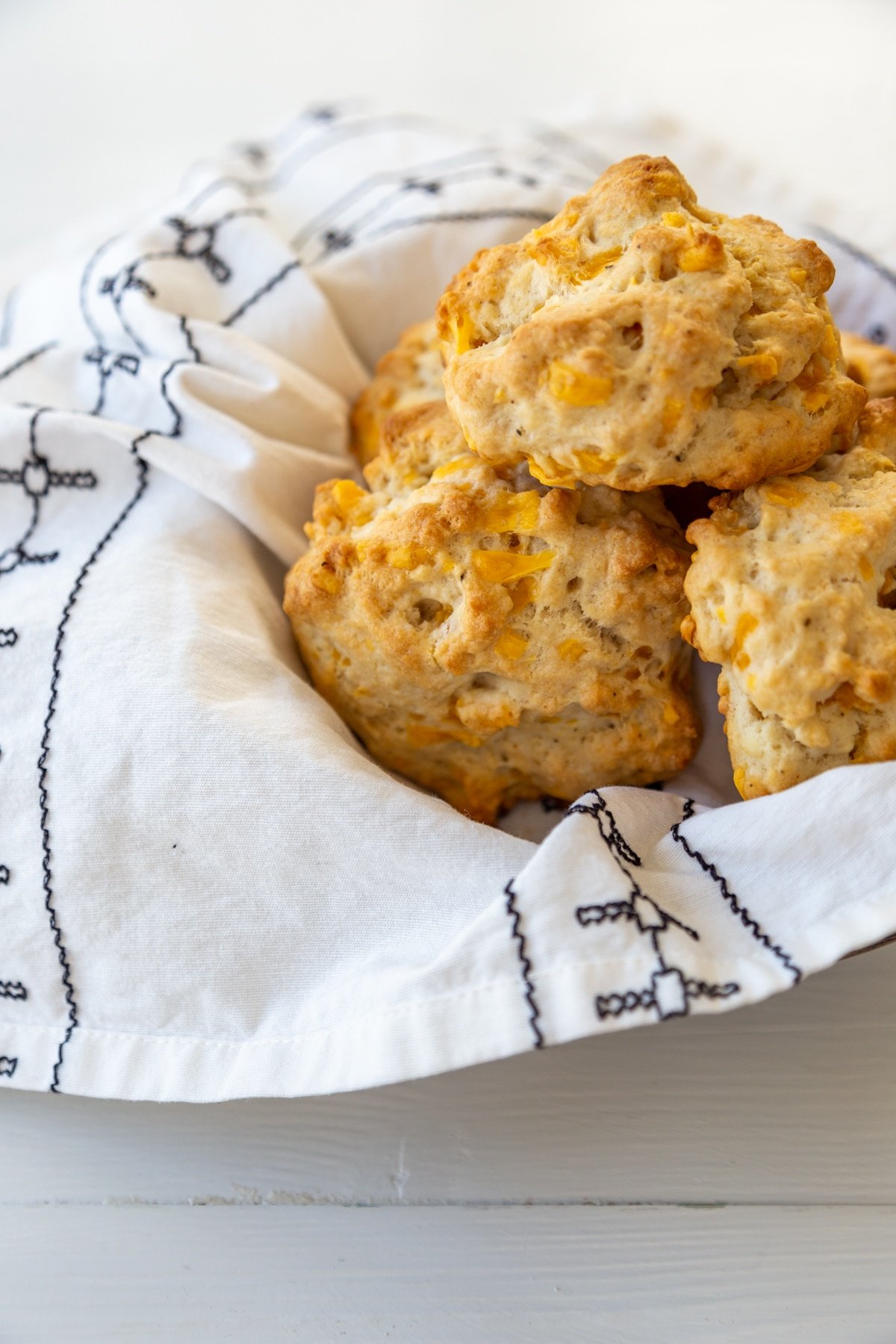 Cheddar drop biscuits in a bowl lined with a white and black patterned napkin.