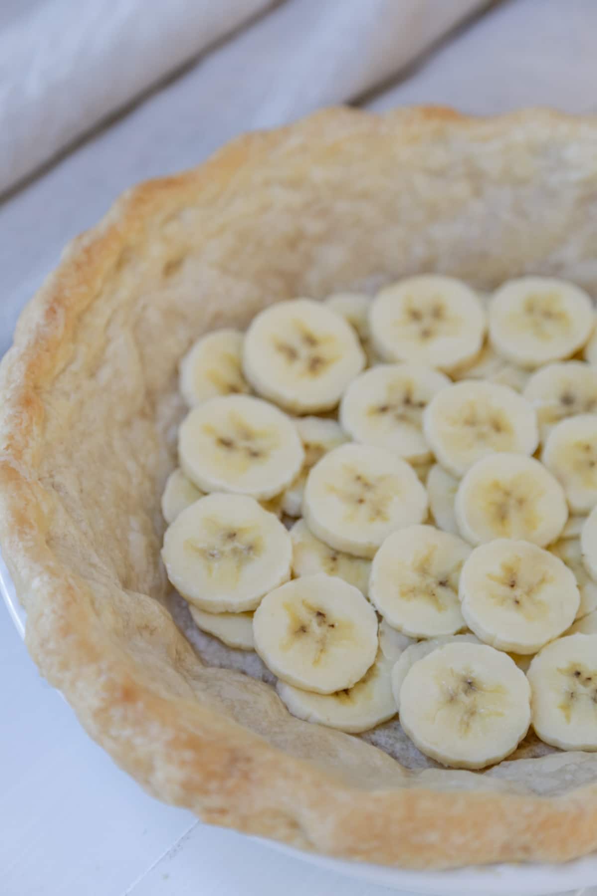 A baked pie crust with a layer of sliced bananas on the bottom of the crust.