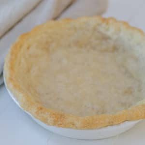 A baked vegan pie crust in a white pie plate.