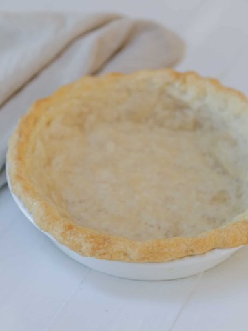 A baked vegan pie crust in a white pie plate.