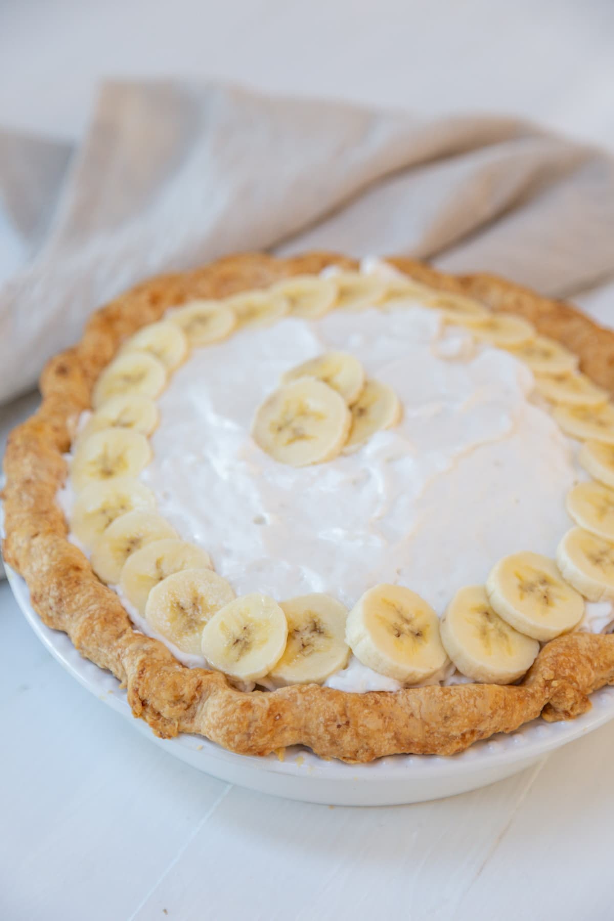 A whole banana cream pie with whipped cream and a ring of banana slices decorating the pie.