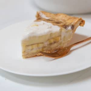 A slice of banana cream pie on a white plate.