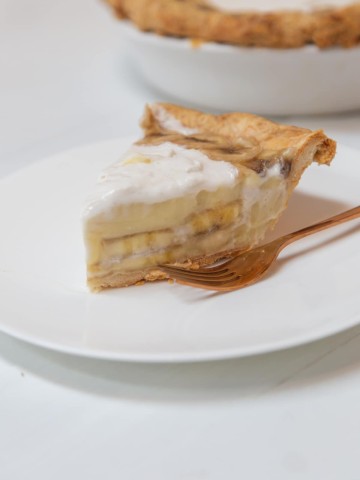 A slice of banana cream pie on a white plate.