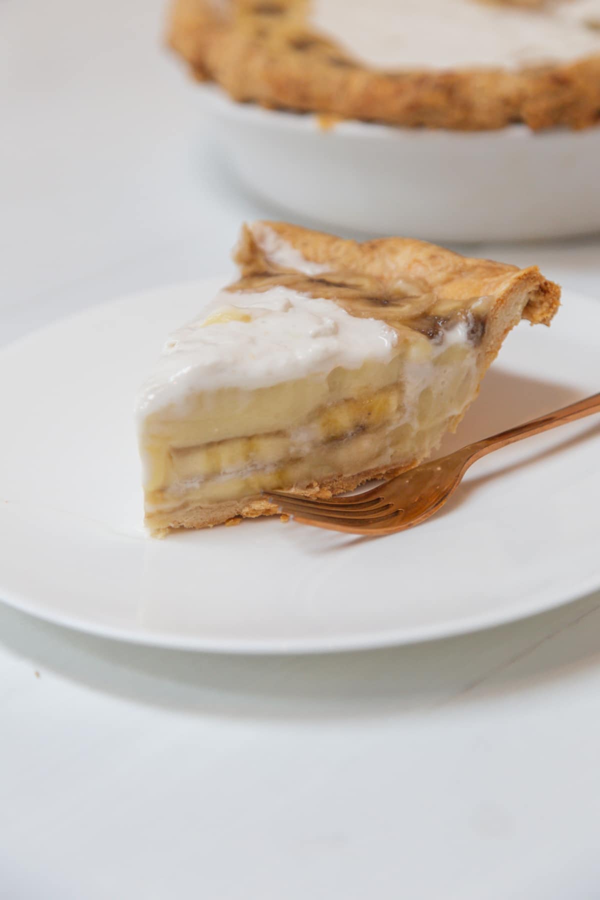 A slice of banana cream pie on a white plate.