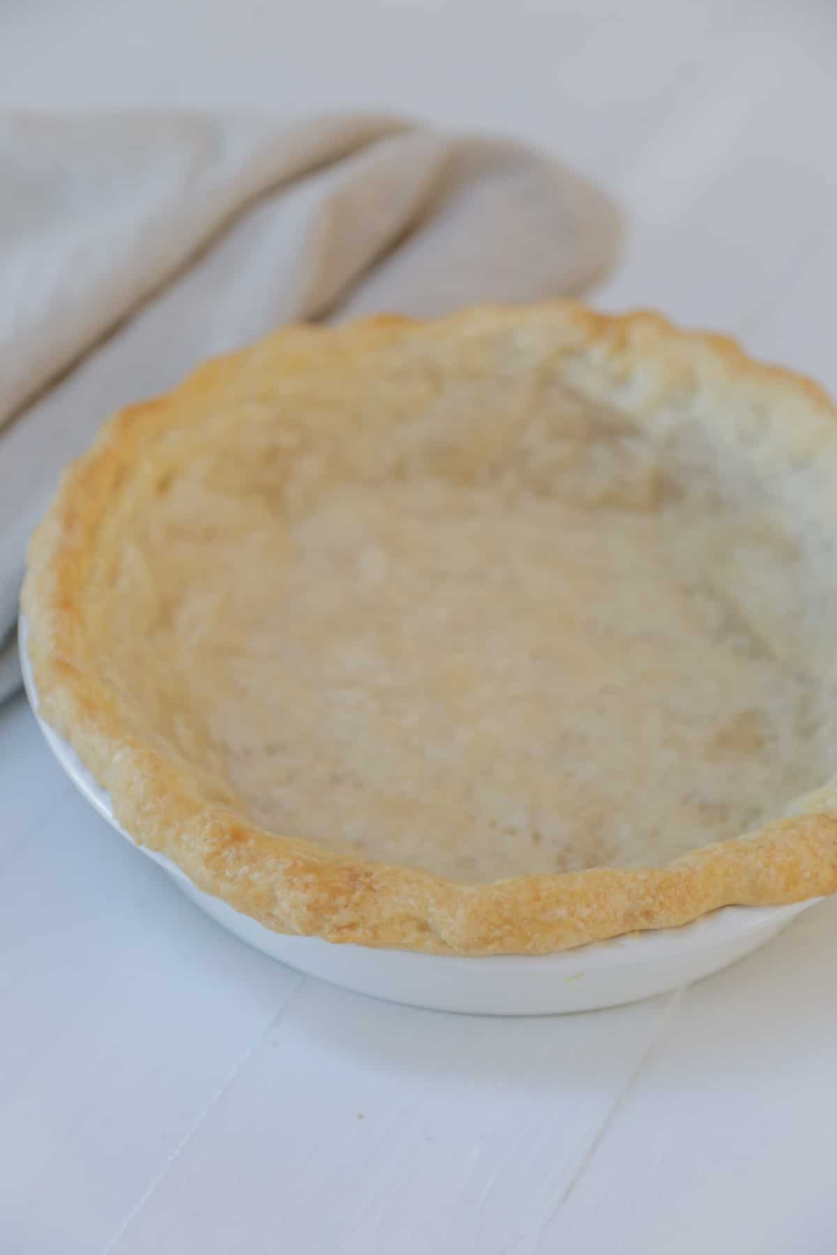 A baked vegan pie crust in a white pie plate.