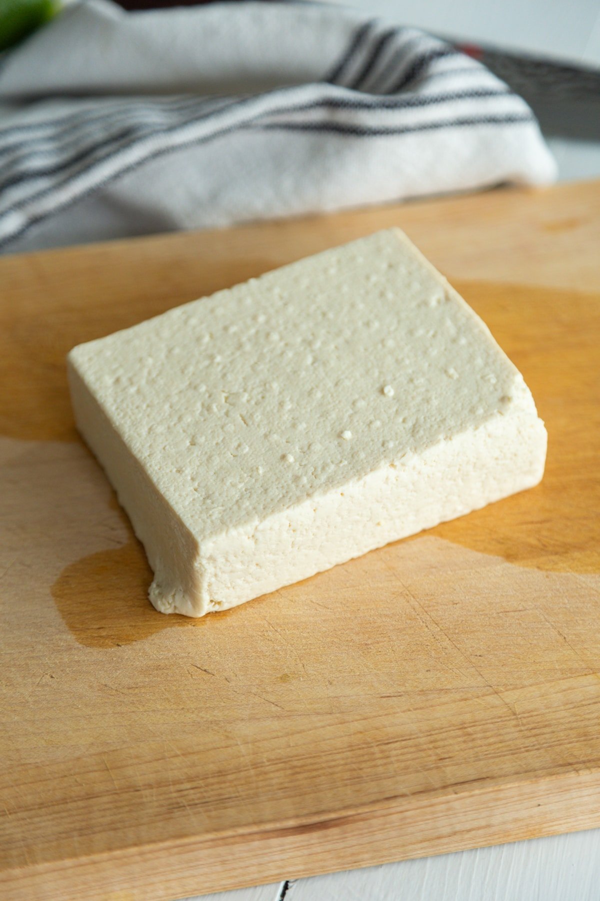 A square piece of tofu on a wooden board.