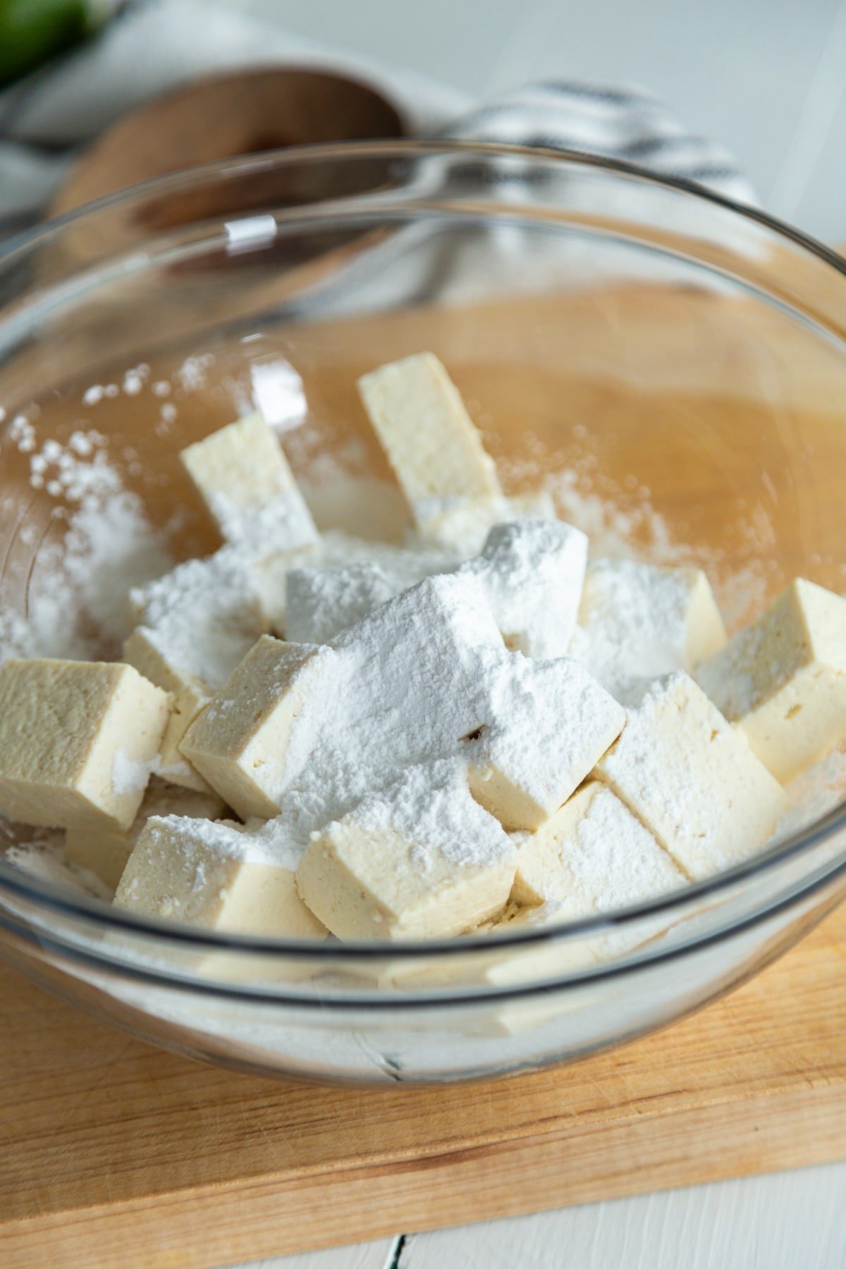 A glass bowl filled with cubed tofu and corn starch