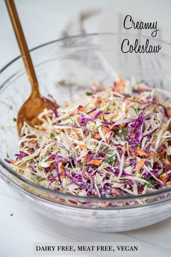A PInterest pin for creamy vegan coleslaw with a picture of the slaw in a clear glass bowl with gold serving pieces in the bowl. 