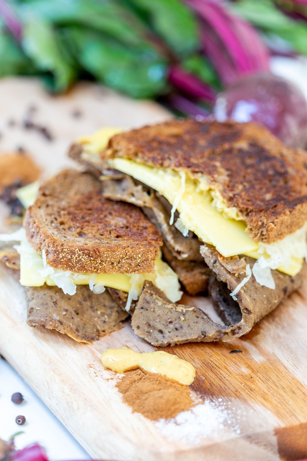 A Reuben sandwich on a wooden board with corned beef and sauerkraut falling out of the sides.