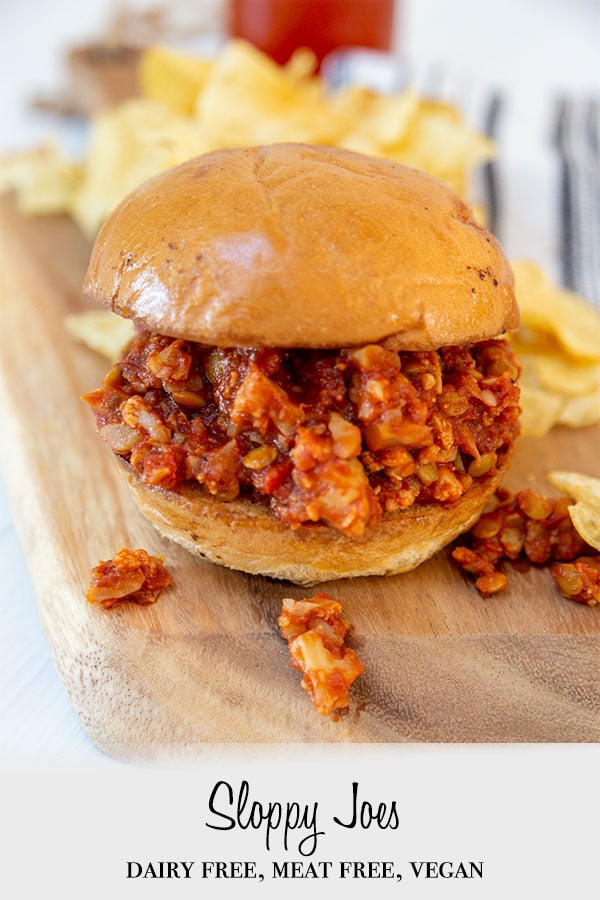 A Pinterest pin for vegan sloppy Joes with a picture of a sloppy Joe sandwich on a wooden board wit potato chips.