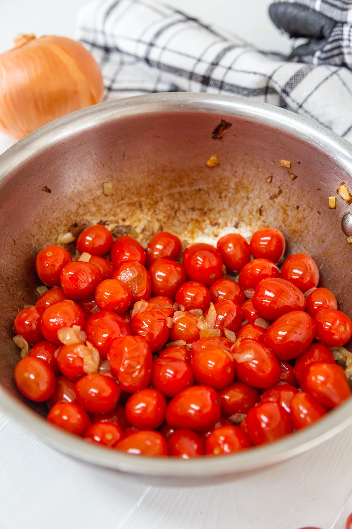 A copper pan with caramelized onions and cherry tomatoes.