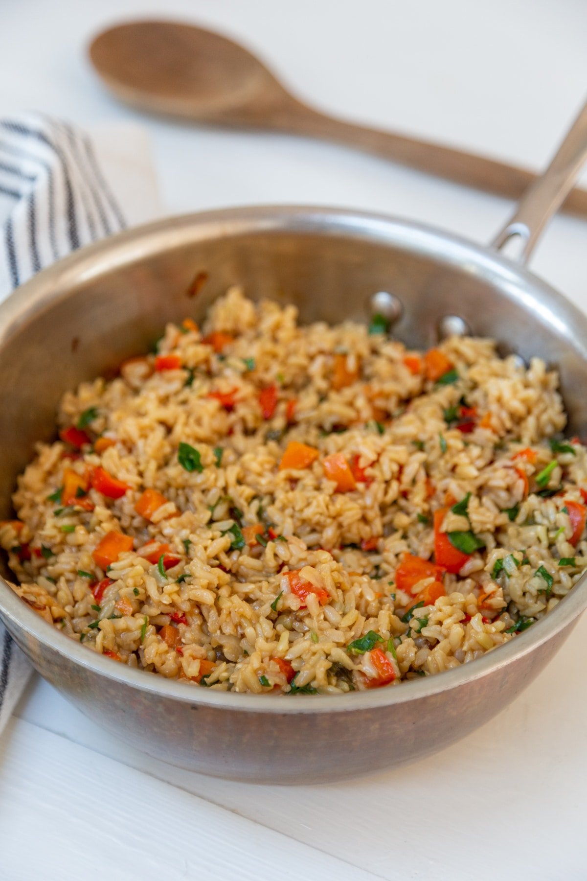 A copper pot with brown rice and mixed vegetables.