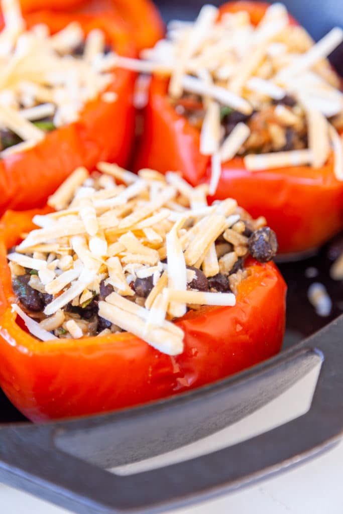red bell peppers stuffed with beans and rice and topped with shredded cheese.
