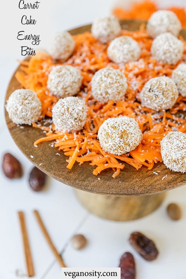 A Pinterest pin for carrot cake bites with a picture of the bites on a layer of shredded carrots on a wood cake stand.