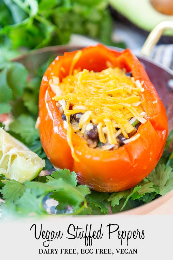 A Pinterest pin for vegan stuffed peppers with a picture of a stuffed pepper with cheese on a plate of cilantro.