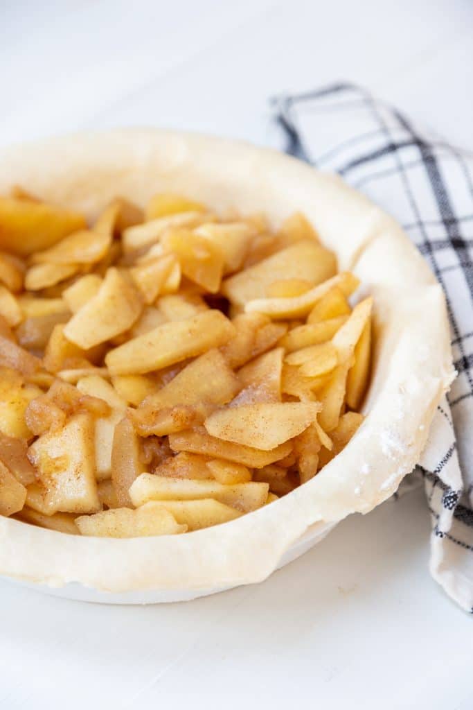 A pie crust in a pie pan filled with cooked apples.