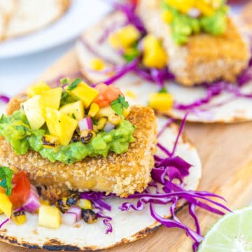 Breaded tofu tacos with mango salsa on a wooden board.