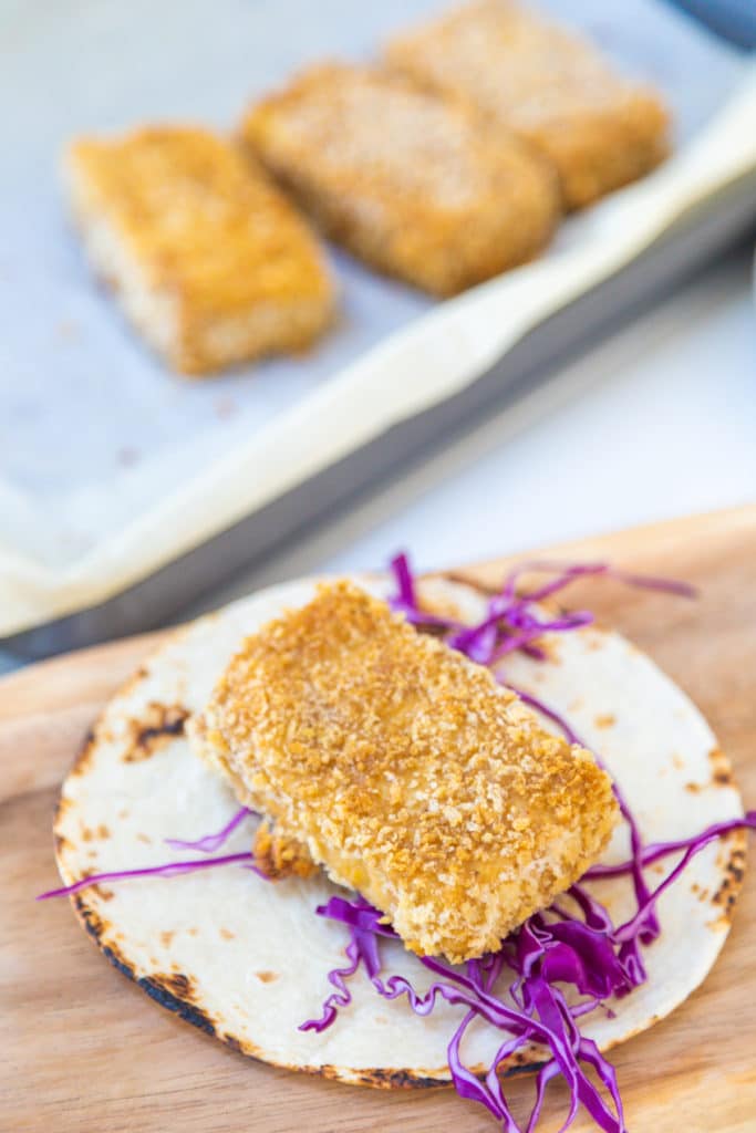 A tortilla with shredded purple cabbage and a breaded fried piece of tofu.