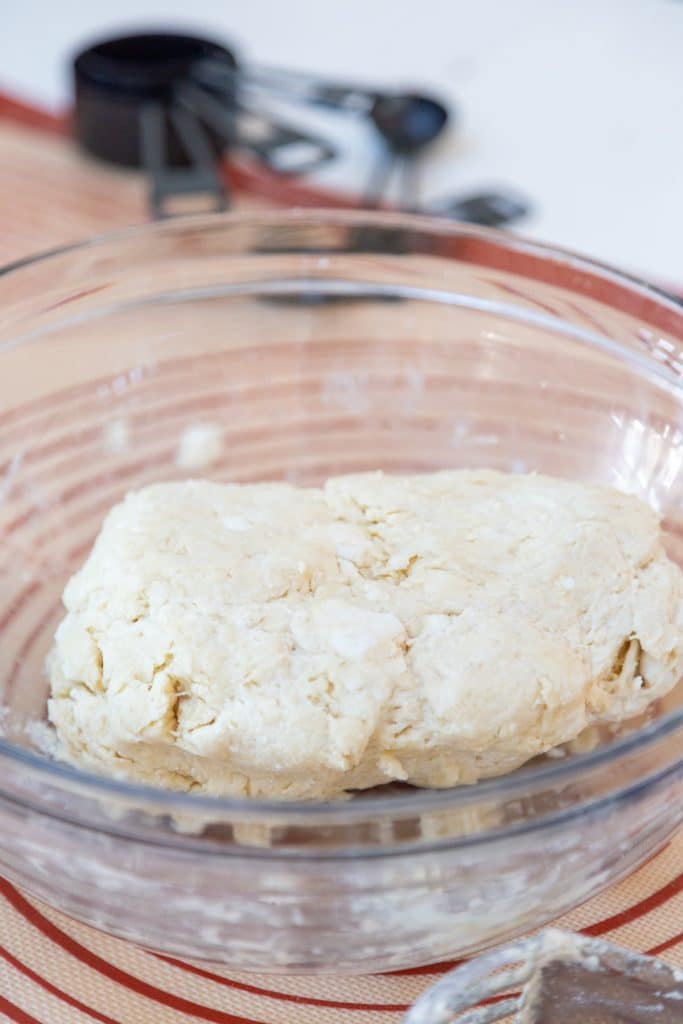 A glass bowl with a ball of pie dough.