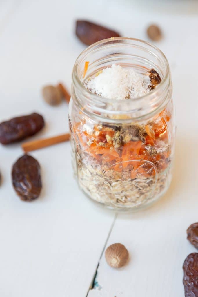 A mason jar with ingredients for carrot cake overnight oats layered inside.