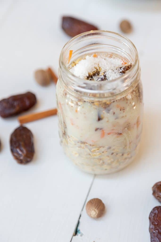 A mason jar with ingredients for carrot cake overnight oats and dates and spices next to the jar.