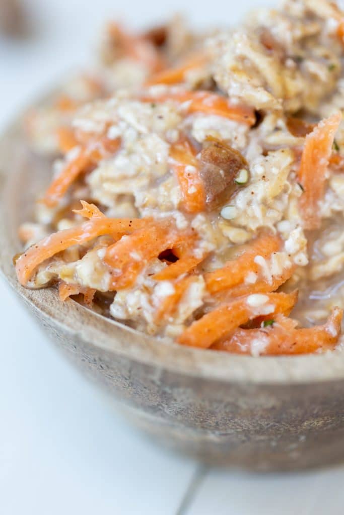 A close up shot of a wooden bowl with carrot cake overnight oats.