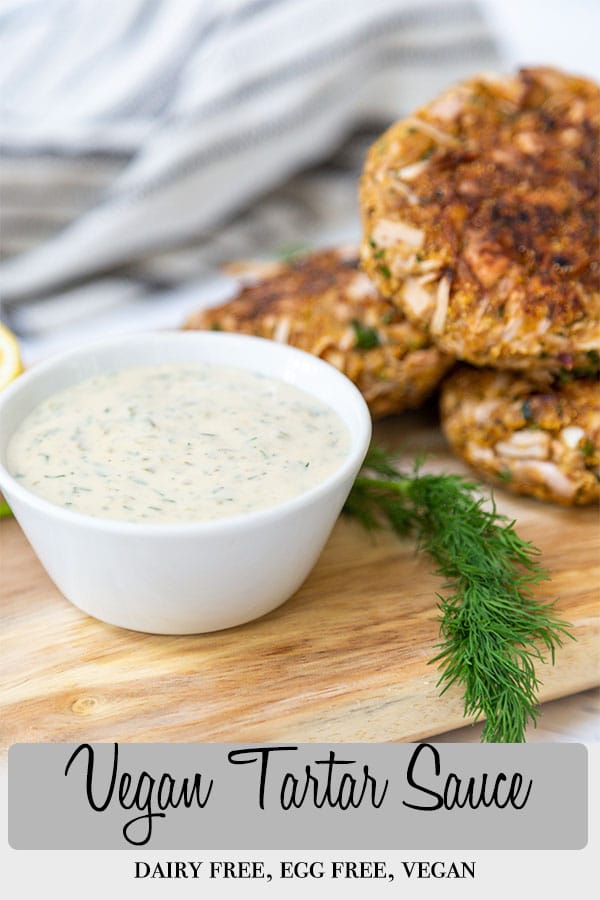 A Pinterest pin for vegan tartar sauce with a picture of the sauce in a white bowl on a wood board with crab cakes and fresh dill.