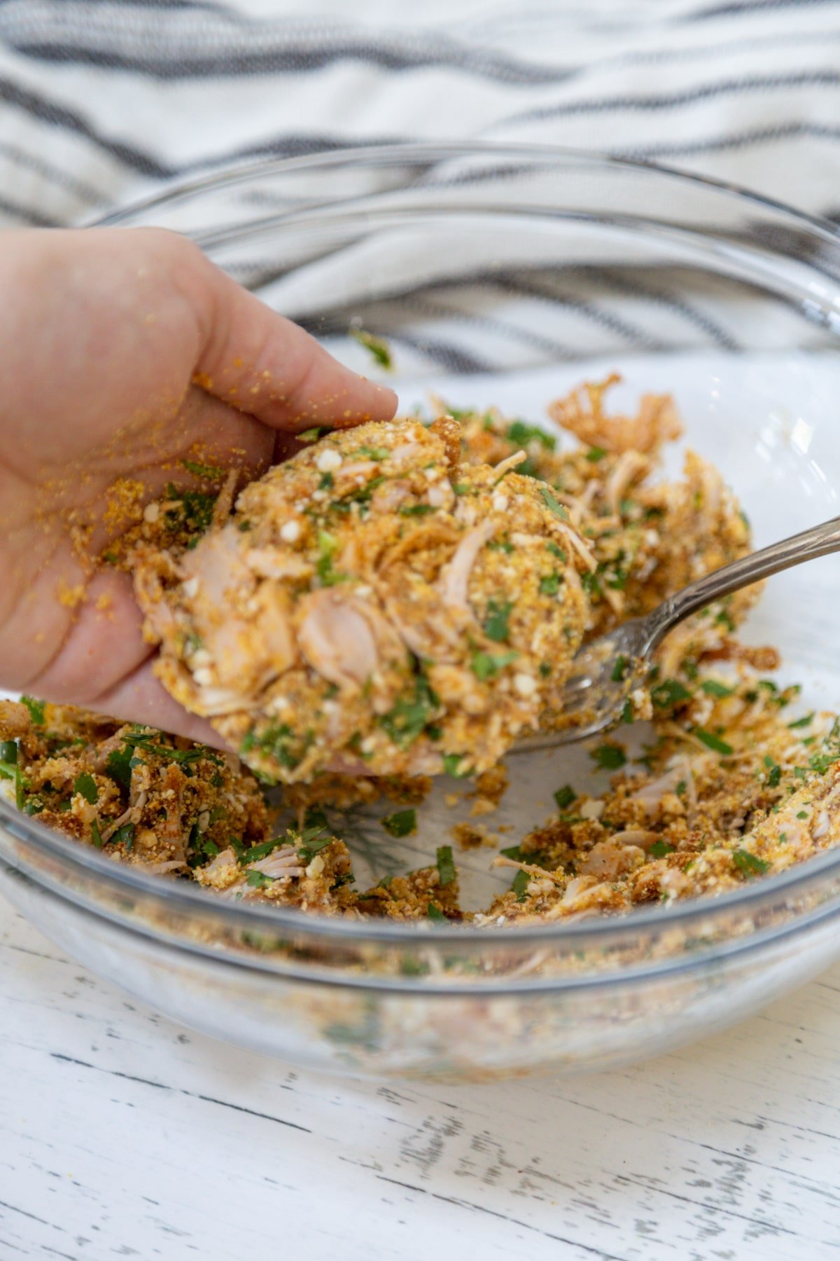 A hand forming crab cake mixture into a patty.